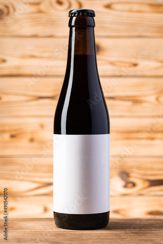 Blank label on the beer bottle on wooden background. photo