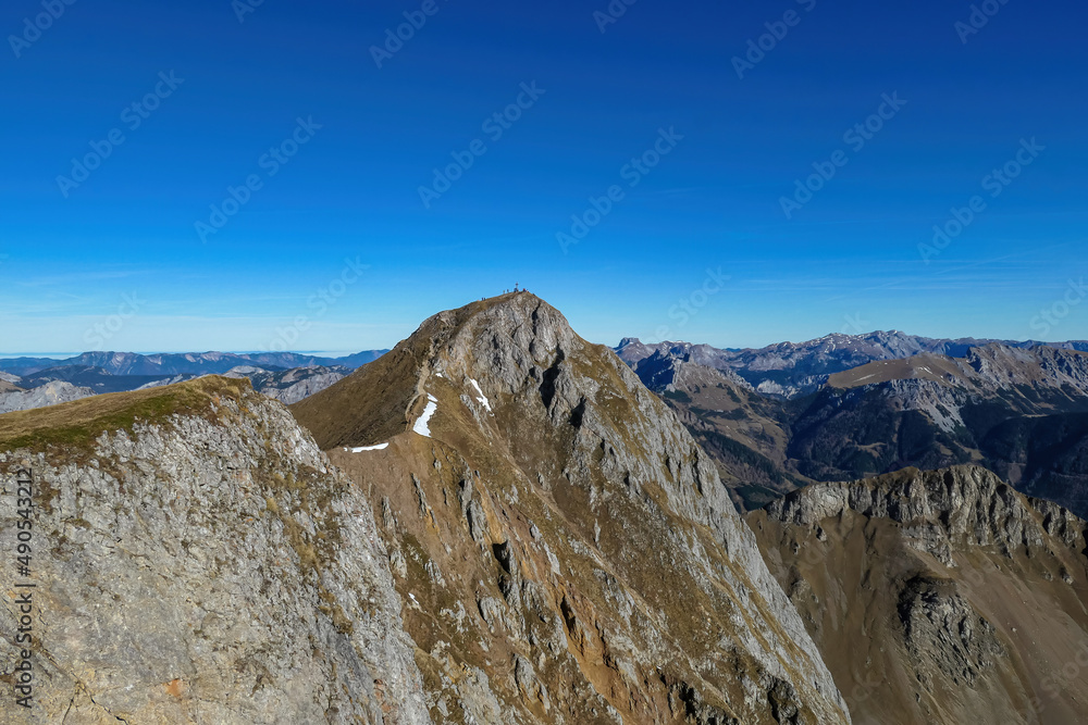 Hiking trail leading to mount Eisenerzer Reichenstein in Styria, Austria, Europe. Austrian Alps. Bare mountain ridges with view on the Ennstal Valley. Summit cross on the peak. Wanderlust. Sunny day