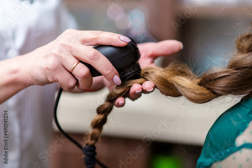 Close-up of hairdresser examining client hair with a special apparatus for diagnostic hair and scalp in a hair shop.