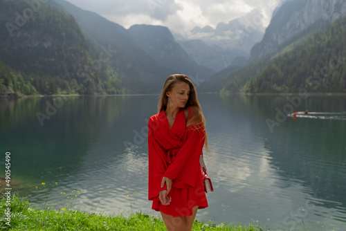 Beautiful girl in a red dress in the mountains near the lake