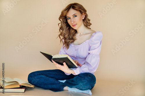Portrait of a positive cheerful student holding a book. The teacher is preparing for the lesson.