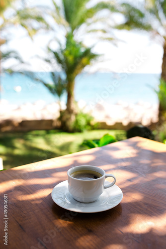 Coffee cup on a wood table over blue sky and sea background. Summer fun, enjoying life, vacations, holidays, tourism, travel concept