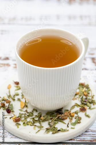 Relax herbal tea on a wooden background. Herbal tea prepared with lemon balm leaves, jasmine flower, apple peel, orange, lemon and hibiscus particles.