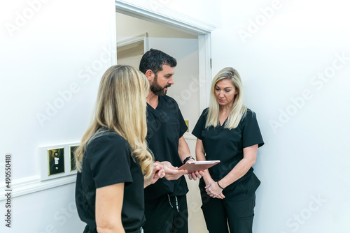 Cuadro en lienzo A male physician doctor at a medical spa and wellness clinic speaking to two fem