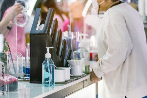 Blue alcohol gel bottle for hand cleaning to prevent the spreading of the Coronavirus (Covid-19) on counter to service for customers at cafe or coffee shop. Healthcare concept. New normal lifestyle.