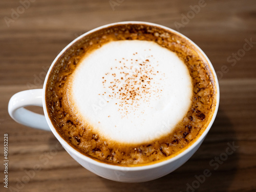 Cappuccino from top view with wooden table.Cup of coffee with copy space.Wood grain. Milk froth floats on top of a cappuccino or latte.wood grain background and coffee cup. coffee cream froth.close up
