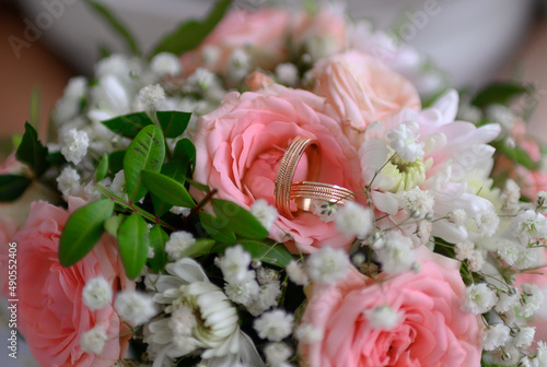 Wedding rings lie on a bouquet of pink and white flowers.