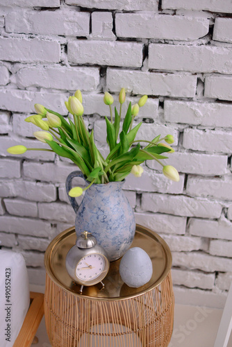 Vase with yellow tulips on a wooden bedside table.