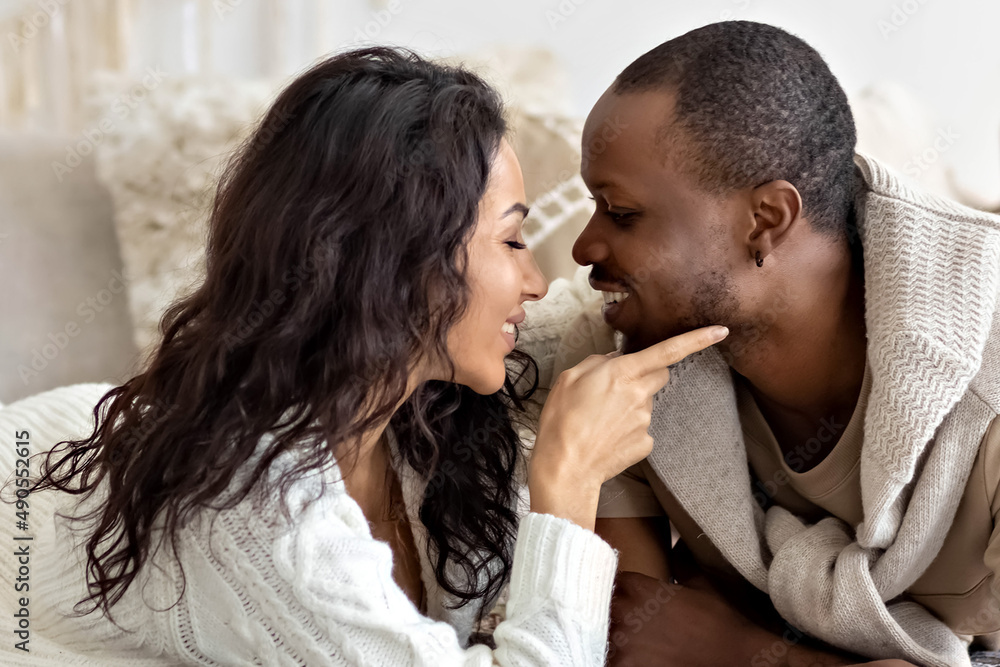 A couple in love - a black man and a woman on a bed in a bright room. Diverse family A couple in love - a black man and a woman on a bed in a bright room. Diverse family