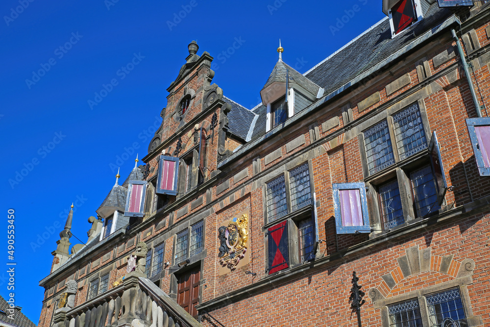 Nijmegen, Netherlands - February 27. 2022: Low angle view on medieval renaissance red brick style facade against cloudless blue sky 