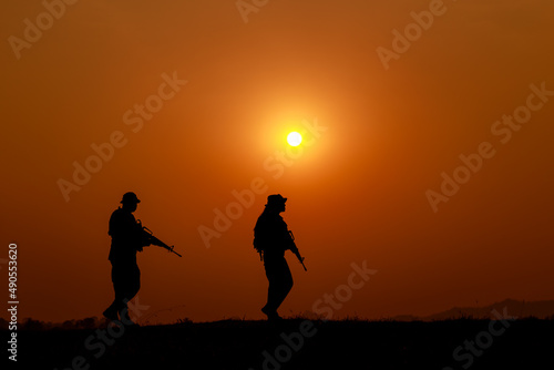 silhouette action soldiers walking and hold weapons background is sunset white balance ship effect