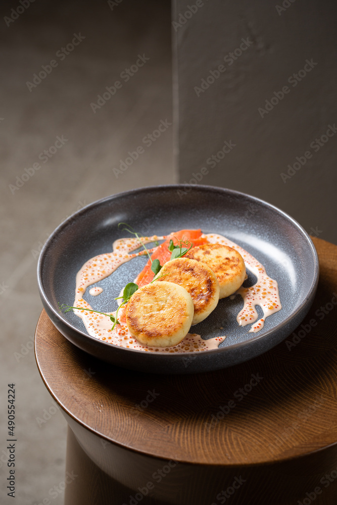 Cottage cheese pancakes, cream sauce with caviar, salmon and greens (  syrniki )
