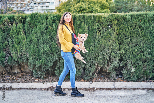 Woman with dog in carrier walking on street photo