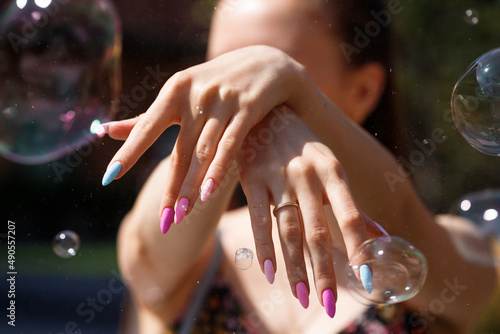 Girl`s hands with a beautiful multicolor manicure, on the background of a blurred silhouette of a girl. 