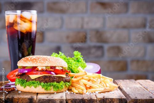 Hamburger with french fries and soft drink with ice on wooden table