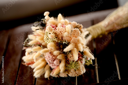 Ramo de novia para boda, flores secas con tonos ocres y rojizos sobre una superficie de madera castaño oscuro