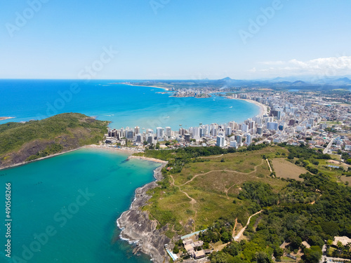 Imagem aéreas da Praia do Morro, linda praia de águas claras e mar manso na região central de Guarapari. Dia ensolarado com praia lotada de barraquinhas, pessoas descansando e praticando esportes.