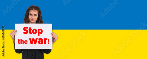 a girl on the background of the flag of Ukraine holds a poster with the text stop the war