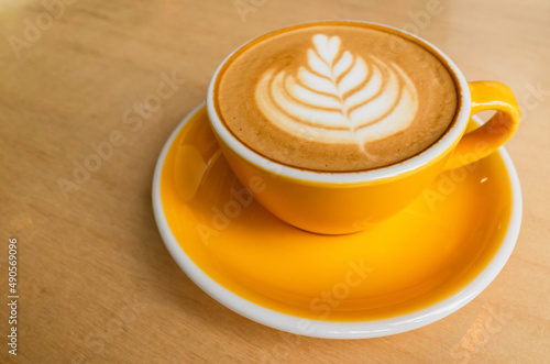 Yellow cup of cappuccino coffee with latte art