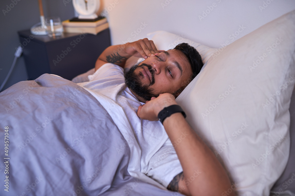 An adult man stretches to wake up, with a Sanskrit tattoo of his name An adult man stretches to wake up, with a Sanskrit tattoo of his name