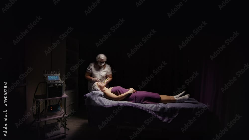 Attractive woman receiving anti-ageing anti-cellulite face massage vacuum rf lifting, spa salon. Wellness body, skin care, face beauty treatment, rejuvenation procedure. Black dark background Attractive woman receiving anti-ageing anti-cellulite face massage vacuum rf lifting, spa salon. Wellness body, skin care, face beauty treatment, rejuvenation procedure. Black dark background