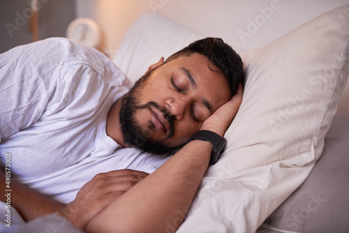 A close up shot of a man sleeping peacefully in bed on his side