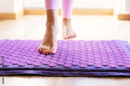 Woman using acupressure mat for feet massage therapy