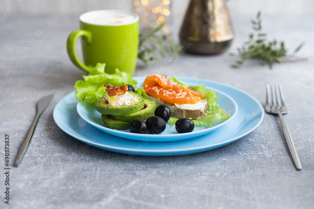 Healthy breakfast. Sandwich with smoked salmon, avocado cheese on lettuce salad leaves and coffee