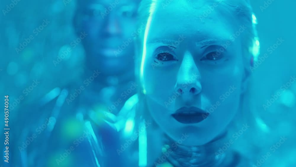 Portrait of beautiful alien woman with dark lips and blackout contact lenses standing with man in room filled with blue neon light and laser beams Portrait of beautiful alien woman with dark lips and blackout contact lenses standing with man in room filled with blue neon light and laser beams