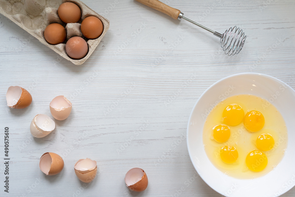 cooking process, eggs in a white bowl on the kitchen table, flat view, breakfast concept cooking process, eggs in a white bowl on the kitchen table, flat view, breakfast concept