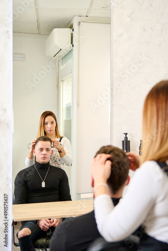 Hairdresser cutting hair and styling a client in the barbershop