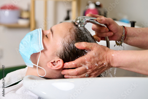 Hairdresser washes the head of a brunette girl with shampoo in the beauty salon