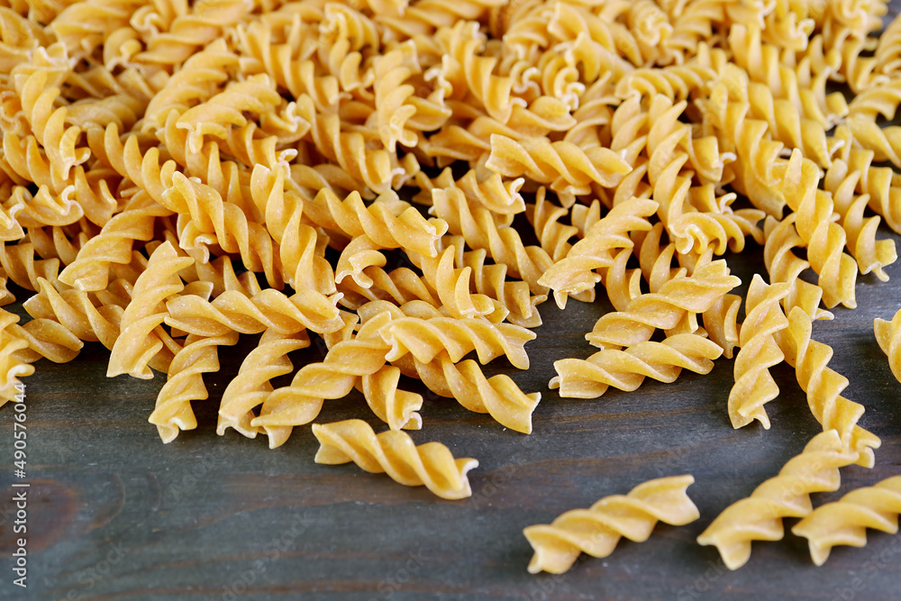 Heap of Uncooked Whole Wheat Fusilli Pasta on Back Wooden Backdrop Heap of Uncooked Whole Wheat Fusilli Pasta on Back Wooden Backdrop