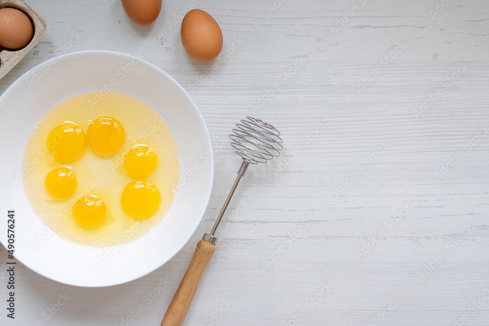 cooking process, eggs in a white bowl on the kitchen table, flat view, breakfast concept cooking process, eggs in a white bowl on the kitchen table, flat view, breakfast concept