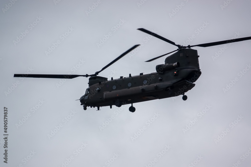 RAF Chinook tandem-rotor CH-47 helicopter flying fast and low in a cloudy blue grey sky on a military battle exercise, Wilts UK RAF Chinook tandem-rotor CH-47 helicopter flying fast and low in a cloudy blue grey sky on a military battle exercise, Wilts UK