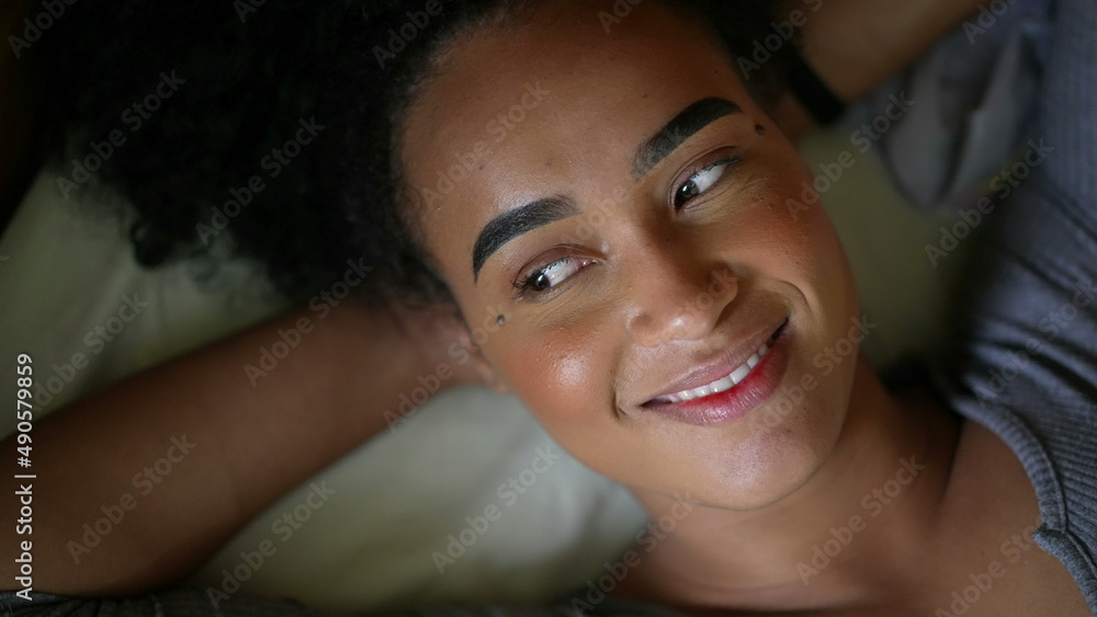 A smiling happy black person lying down in bed feeling happy A smiling happy black person lying down in bed feeling happy