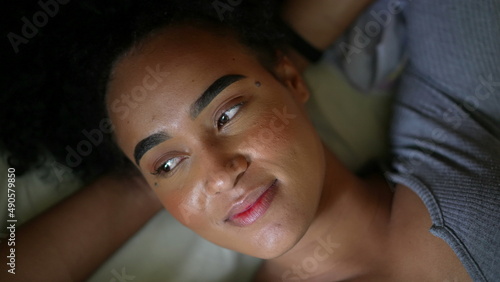 A smiling happy black person lying down in bed feeling happy