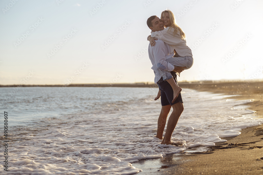 Full length of carefree couple having fun standing on seashore at sunset