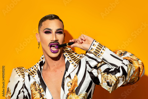 Obraz na płótnie Glamorous drag queen portrait biting lipstick on a yellow background