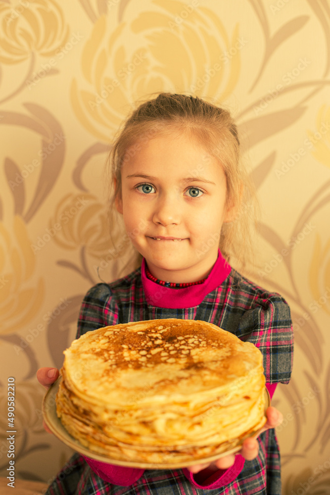 A girl holds a plate with a stack of pancakes. A girl holds a plate with a stack of pancakes.