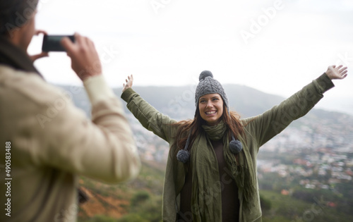 Make sure you get the view. A young couple taking a photo while hiking in the mountains.