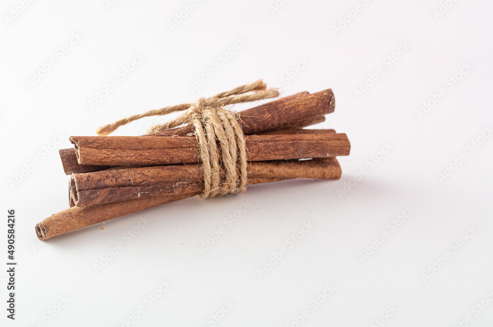 Several cinnamon sticks. Cinnamon in a pile. A bunch of cinnamon tied with a rope. Cinnamon on a white background.