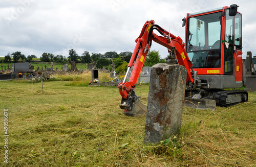 Canvas Print An excavator for digging a grave in a cemetery for burial or exhumation