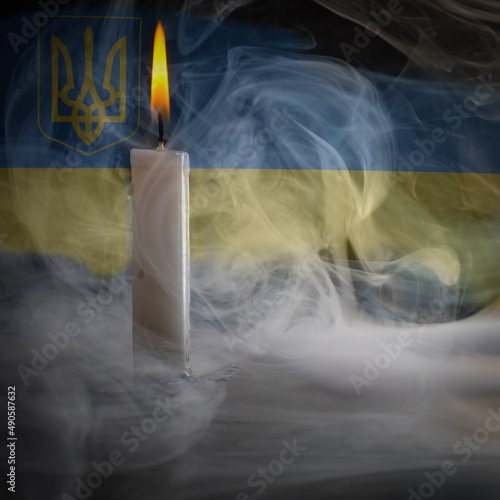 burning candle on the background of the flag of ukraine. remember the dead. war, aggression.
