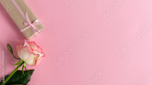 Pink rose with gift on pink background. Concept of Valentine's day, mother's day, women's day and birthday. Greetings card. Copy space and Flat lay.