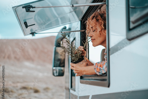 Happy travel summer holiday vacation with camper van vehicle concept lifestyle with pretty adult young woman enjoying freedom and campsite outside the window of her alternative home on wheels