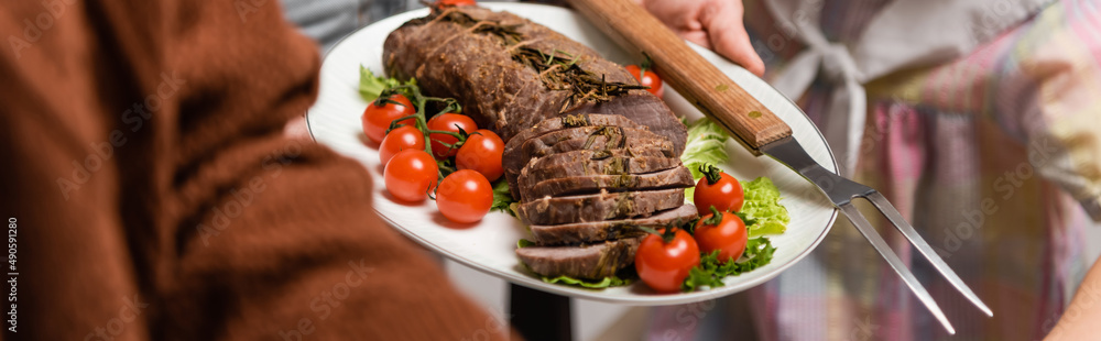 selective focus of fried meat with fresh vegetables near cropped family, banner. selective focus of fried meat with fresh vegetables near cropped family, banner.