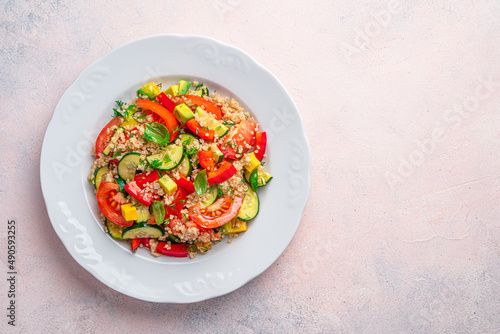 Vegetarian portion, salad with quinoa and fresh vegetables on a light background.