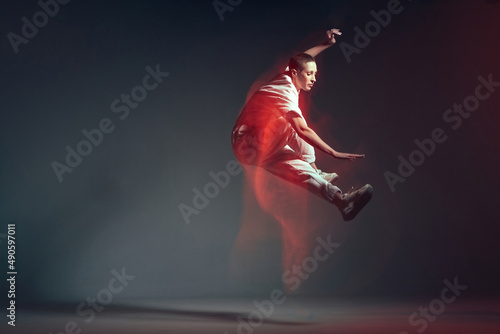 Dancing energetic jumping sporty girl in motion, dance freestyle. Breakdancer in red neon studio light. Long exposure