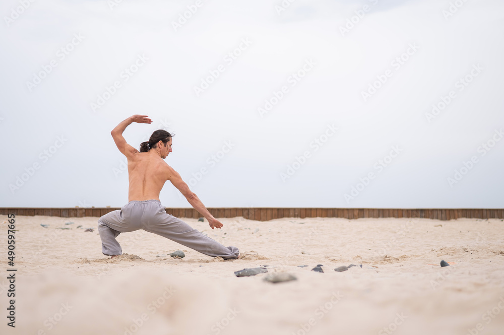 Caucasian man with long hair practicing qigong outdoors. Caucasian man with long hair practicing qigong outdoors.